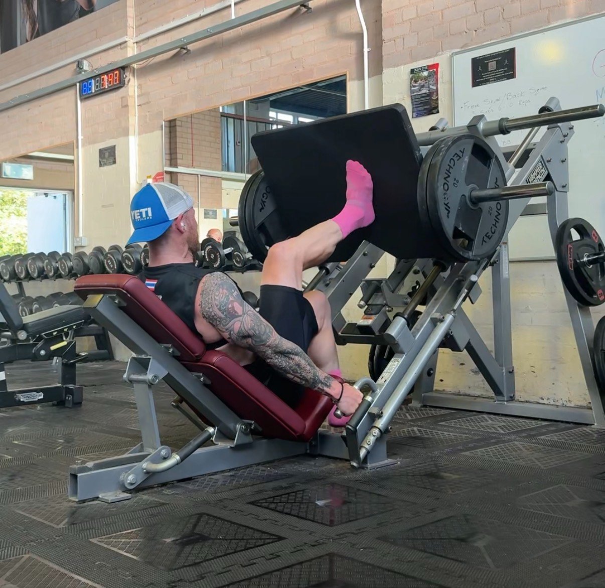 A middle-aged runner in training kit performing a heavy barbell squat in a gym