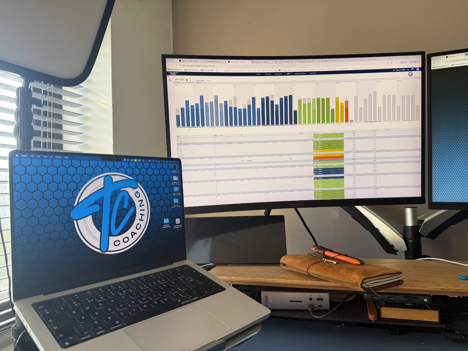 An amateur endurance athlete reviewing a season of training data on a laptop at a kitchen table in morning light.